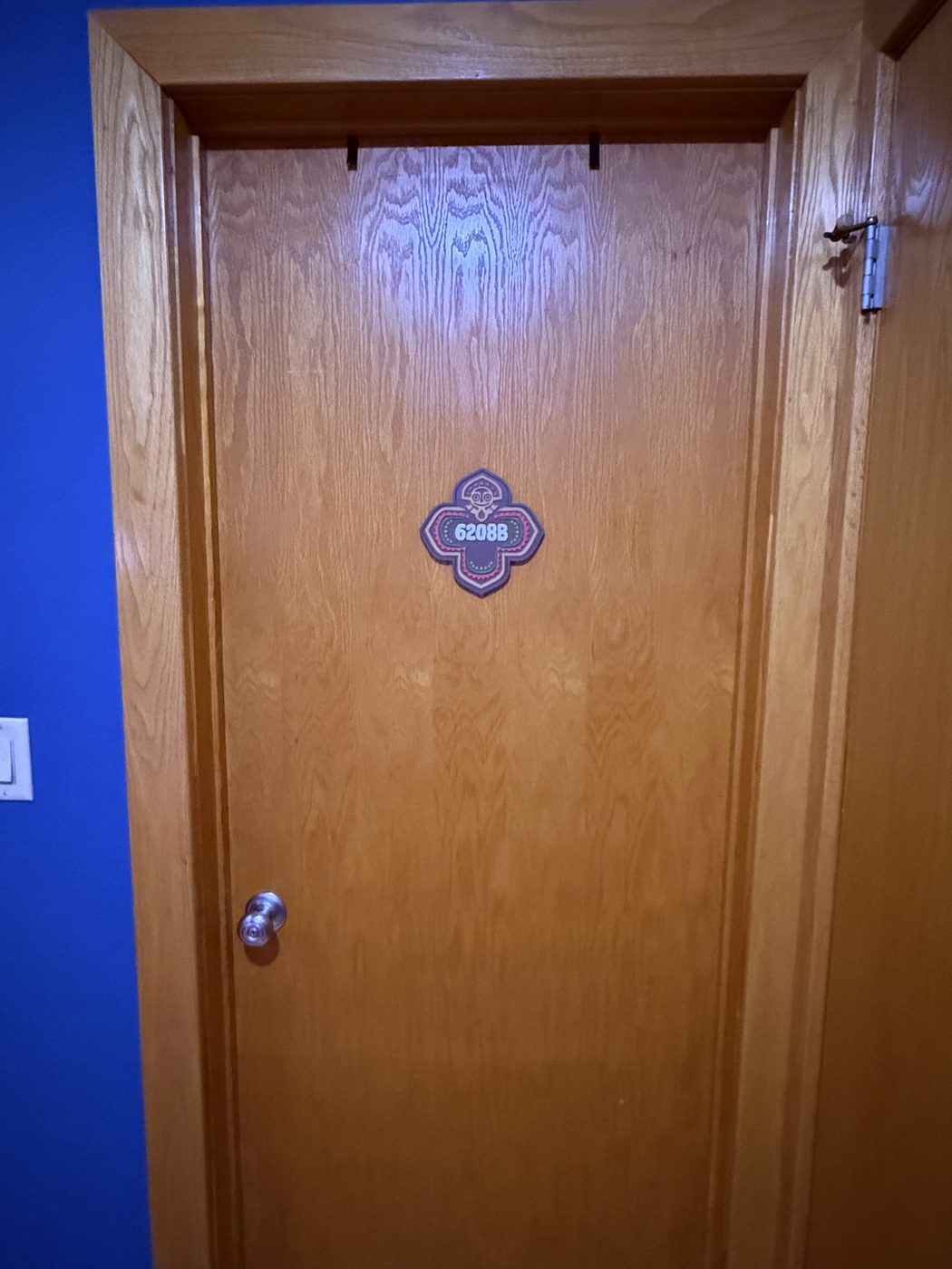 The wooden entry door to room 6208B with a tiki-styled room number plaque
