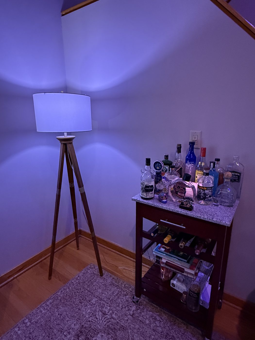The tiki bar cart stocked with spirits and tiki mugs under moody purple lighting