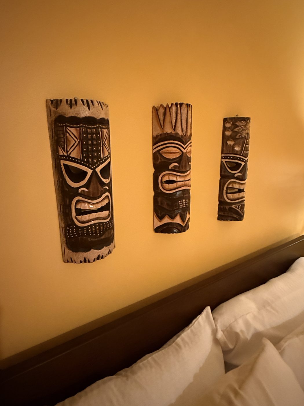 Three hand-carved tiki masks mounted above the headboard